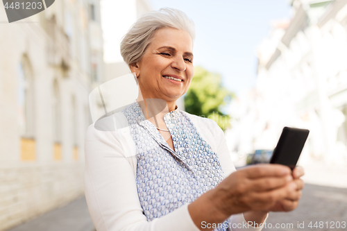 Image of happy senior woman with smartphone in summer