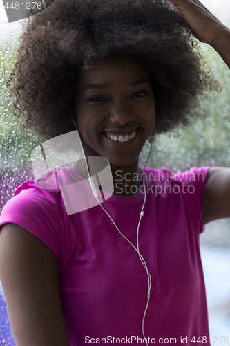 Image of portrait of young afro american woman in gym while listening mus