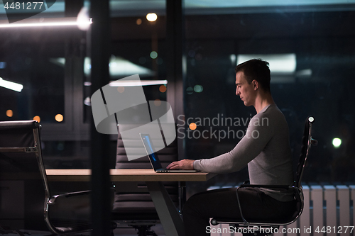 Image of man working on laptop in dark office