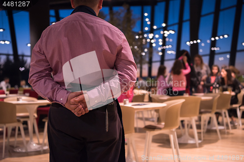 Image of waiter standing with hands behind his back