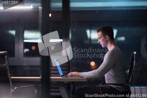 Image of man working on laptop in dark office