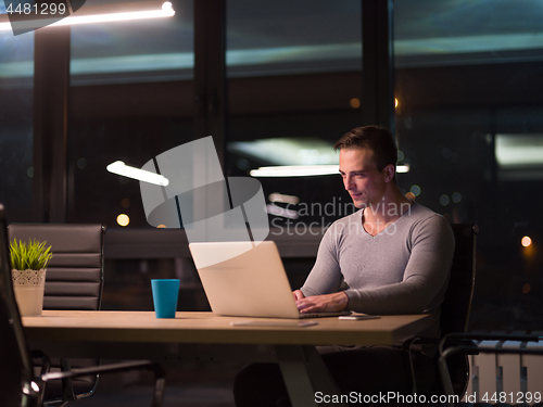 Image of man working on laptop in dark office