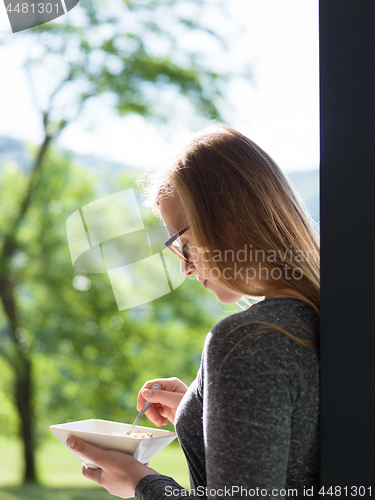 Image of woman eating breakfast in front of her luxury home villa