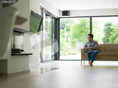 Image of Man using laptop in living room