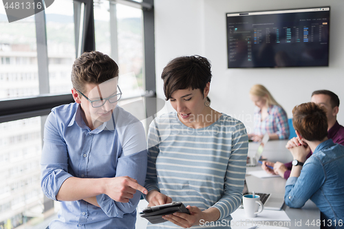 Image of Two Business People Working With Tablet in office
