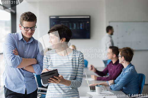 Image of Two Business People Working With Tablet in office