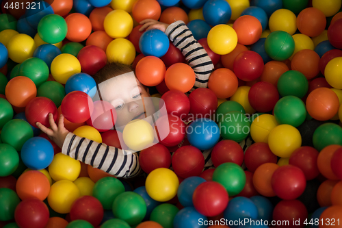 Image of boy having fun in hundreds of colorful plastic balls