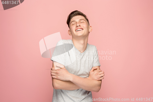 Image of The happy businessman standing and smiling against pink background.