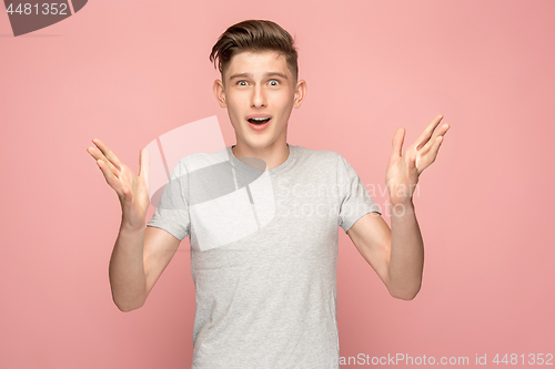 Image of The young attractive man looking suprised isolated on pink