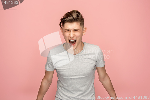 Image of The young emotional angry man screaming on pink studio background