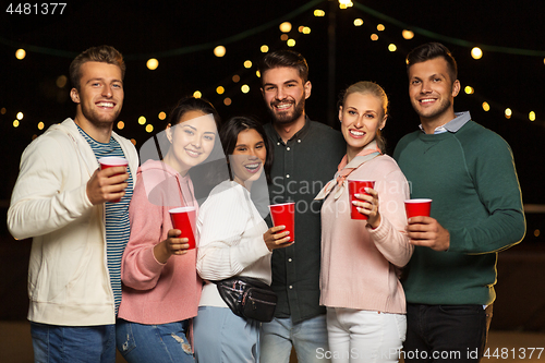 Image of friends with party cups on rooftop at night