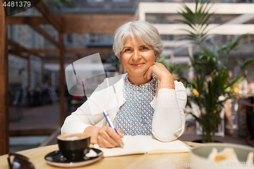 Image of senior woman with notebook and coffee at cafe