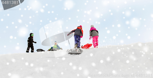 Image of kids with sleds climbing snow hill in winter