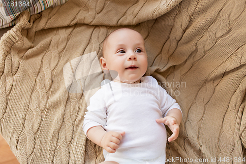 Image of sweet little baby boy lying on knitted blanket