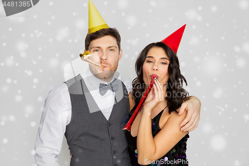 Image of happy couple with party blowers having fun