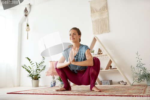 Image of young woman doing garland pose at yoga studio