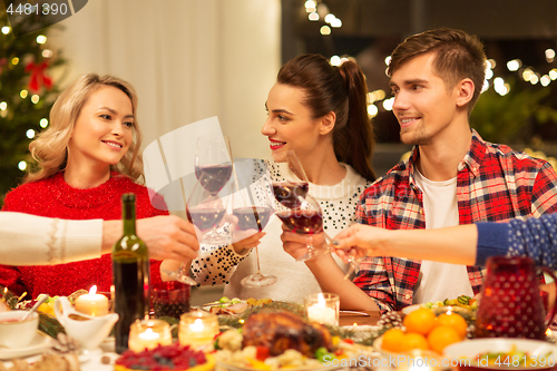 Image of happy friends drinking red wine at christmas party