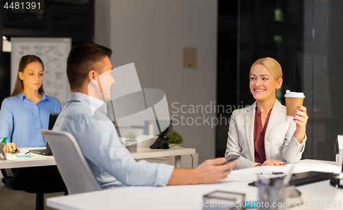 Image of business people drinking coffee at night office