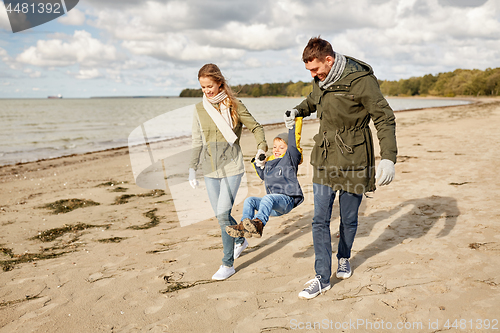 Image of happy family walking along autumn beach