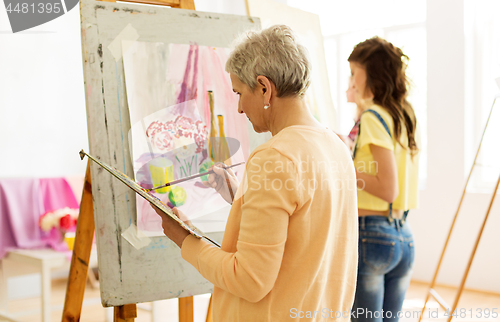 Image of senior woman painting at art school studio
