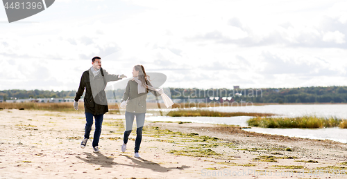 Image of couple running along autumn beach