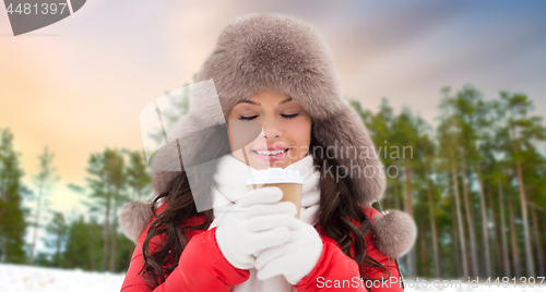 Image of woman in fur hat with coffee over winter forest