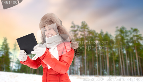 Image of woman in fur hat with tablet pc over winter forest