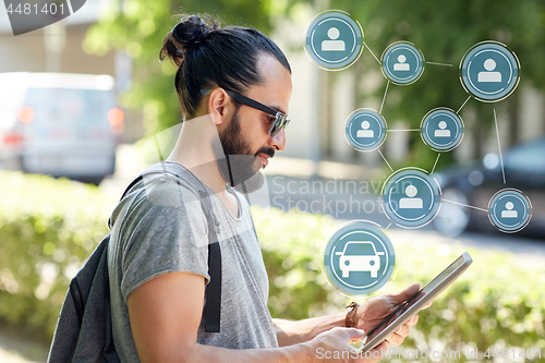 Image of man using car sharing app on tablet pc in city