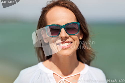 Image of happy smiling woman in sunglasses on summer beach