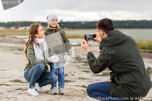 Image of family photographing by smartphone on autumn beach