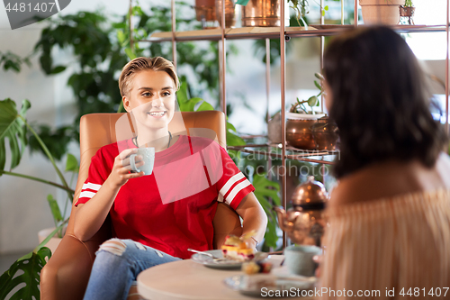 Image of female friends drinking coffee and talking at cafe