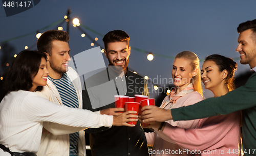 Image of friends clinking party cups on rooftop at night