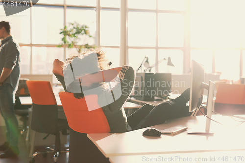 Image of businessman sitting with legs on desk