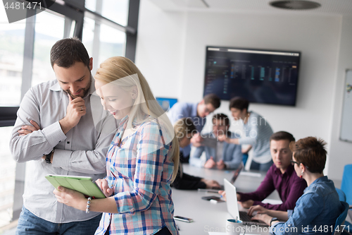 Image of Two Business People Working With Tablet in office