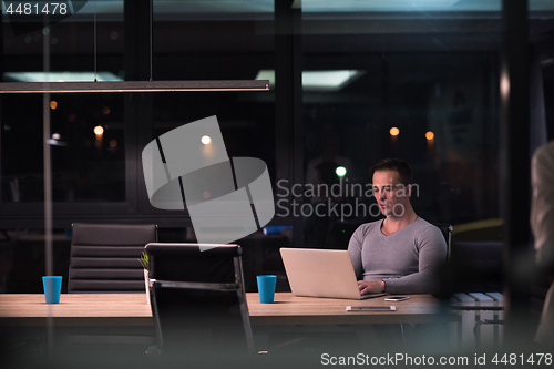 Image of man working on laptop in dark office