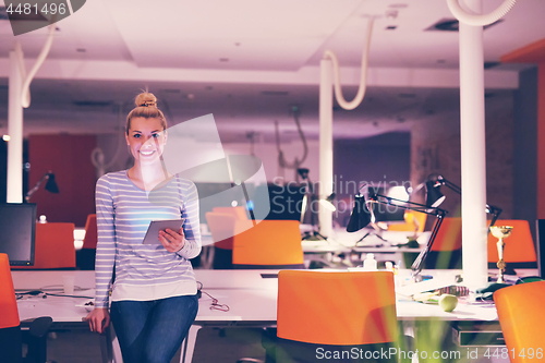 Image of woman working on digital tablet in night office