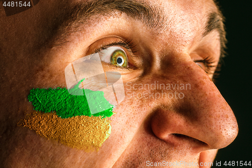 Image of Portrait of a man with the flag of the Brazil painted on him face.