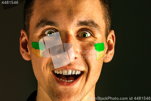 Image of Portrait of a man with the flag of the Brazil painted on him face.