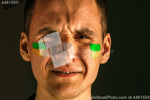 Image of Portrait of a man with the flag of the Brazil painted on him face.