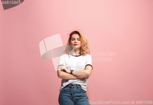 Image of The serious business woman standing and looking at camera against pink background.