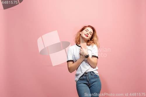 Image of The happy business woman is smiling and keeping in hand the smartphone against pink background.