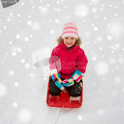 Image of happy girl riding sled on snow in winter