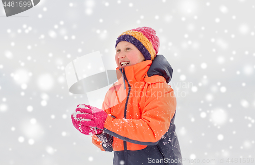 Image of happy girl playing with snow in winter