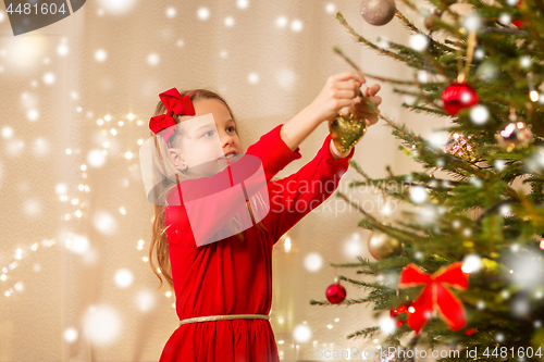 Image of happy girl in red dress decorating christmas tree