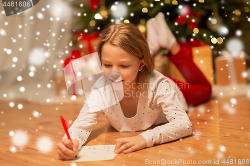 Image of smiling girl writing christmas wish list at home