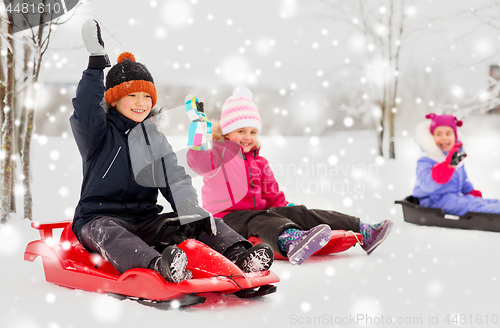 Image of happy little kids sliding on sleds in winter