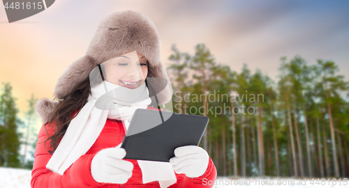 Image of woman in fur hat with tablet pc over winter forest