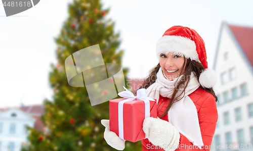 Image of happy woman with gift over christmas tree