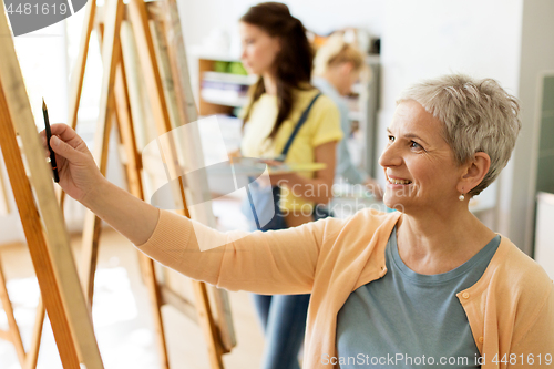 Image of senior woman drawing on easel at art school studio