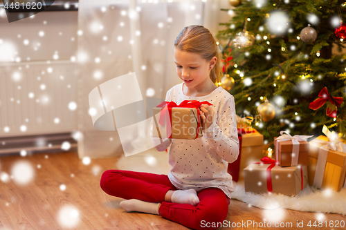 Image of smiling girl with christmas gift at home